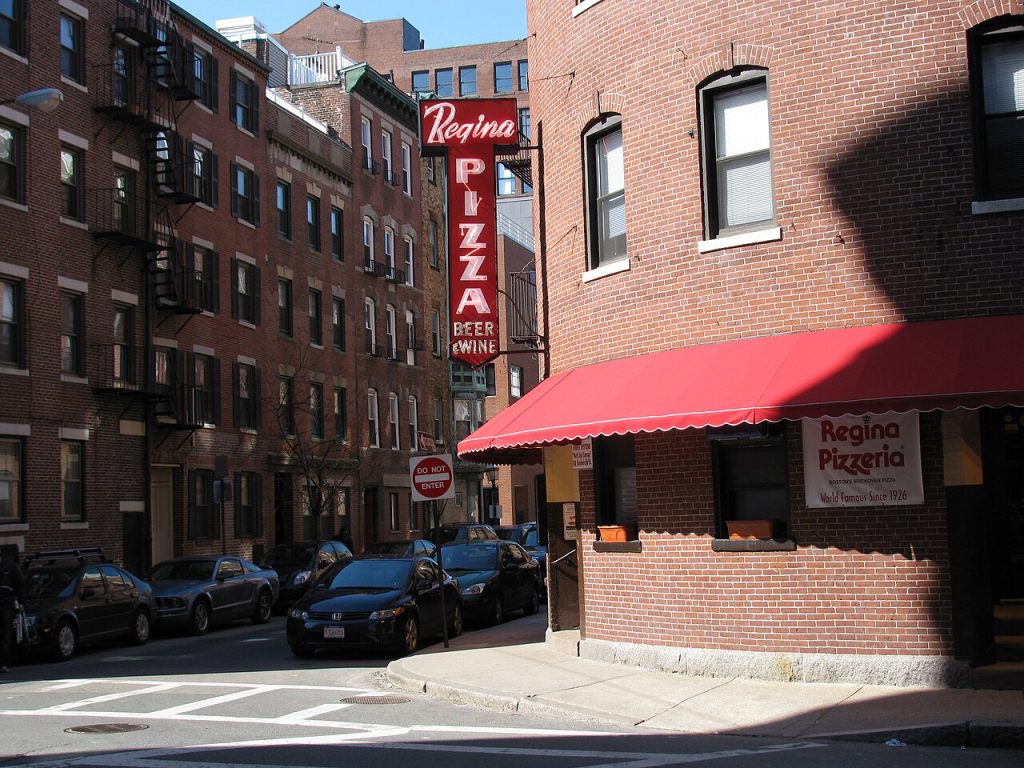 Regina Pizzeria red sign and awning on its brick building in Boston’s North End.